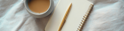 Overhead picture of mug of chai and notebook and gold pen on cream linen table cloth
